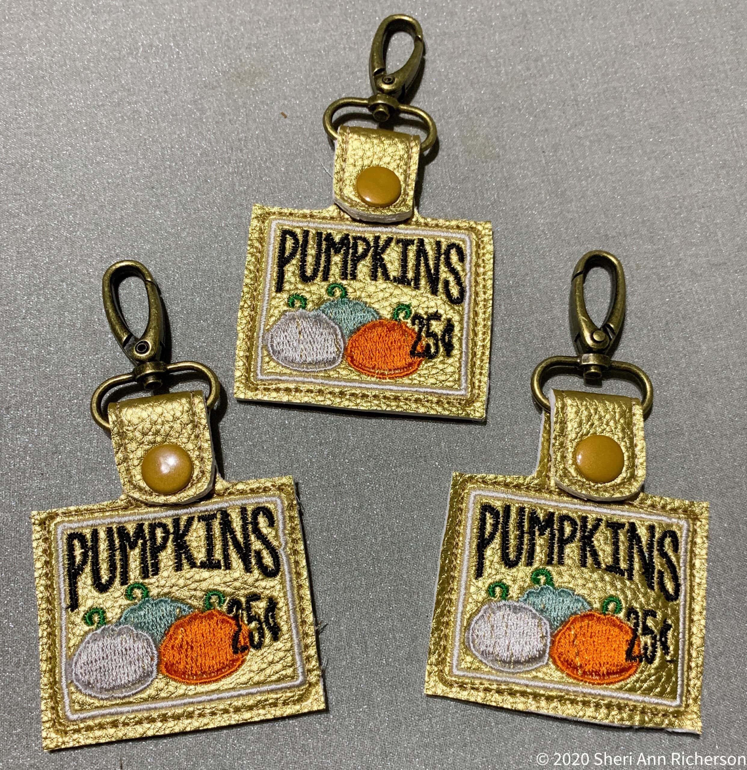 Embroidered pumpkin patch keychain accessories with vintage gold leather accents.