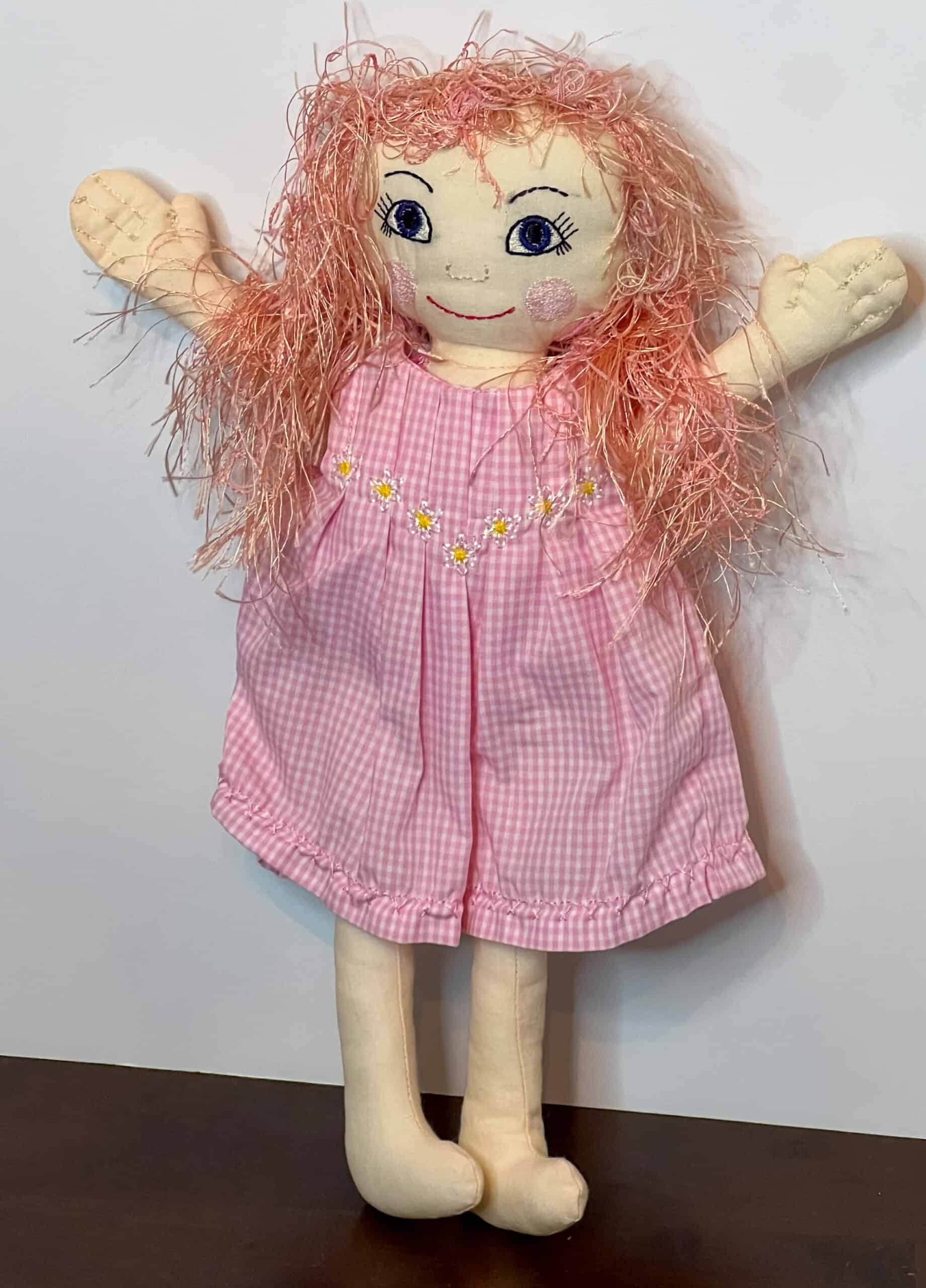 Handmade fabric doll with pink gingham dress and pink yarn hair.