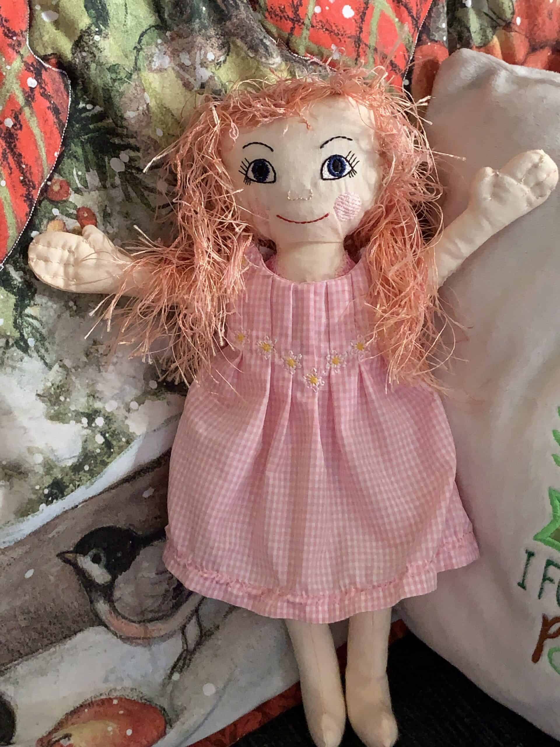 Knitted doll with pink dress and curly orange hair.