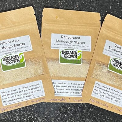 Dehydrated sourdough starter packets on a black surface with handwritten label reading "Approximately 5 teaspoons.".