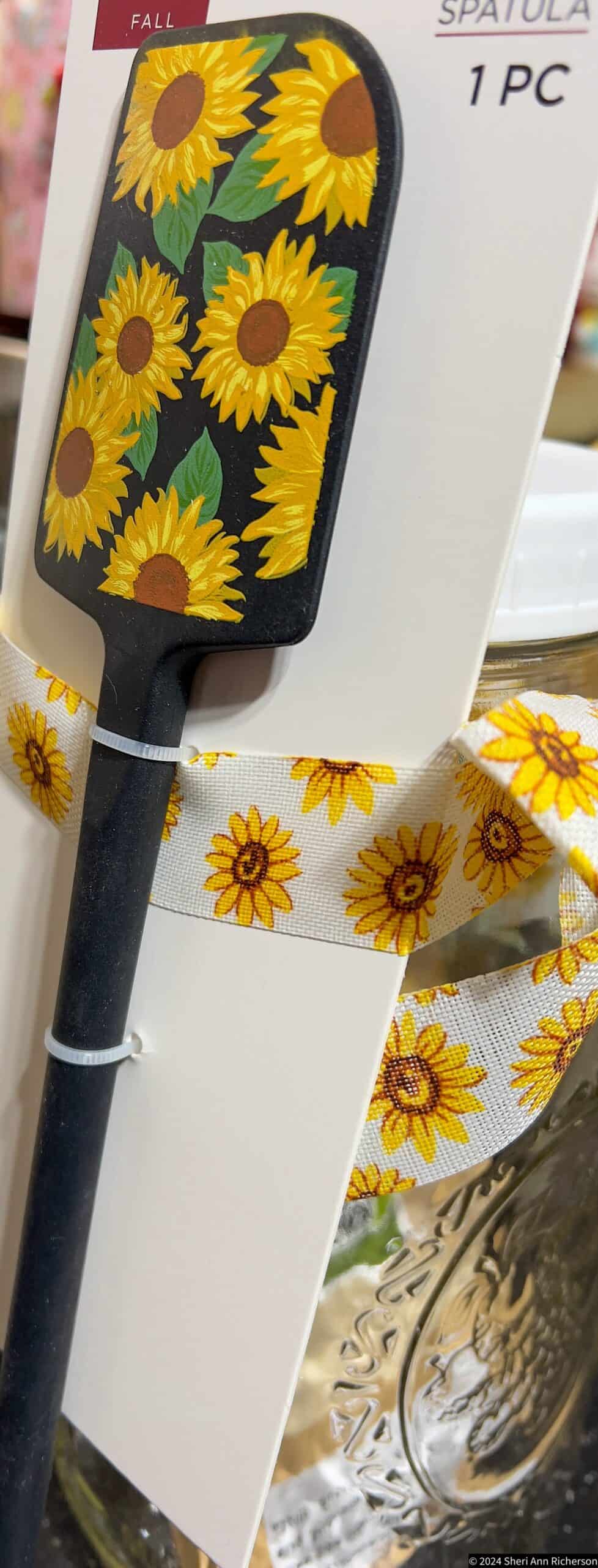 Sunflower-patterned spatula with black handle, perfect for rustic kitchen decor.